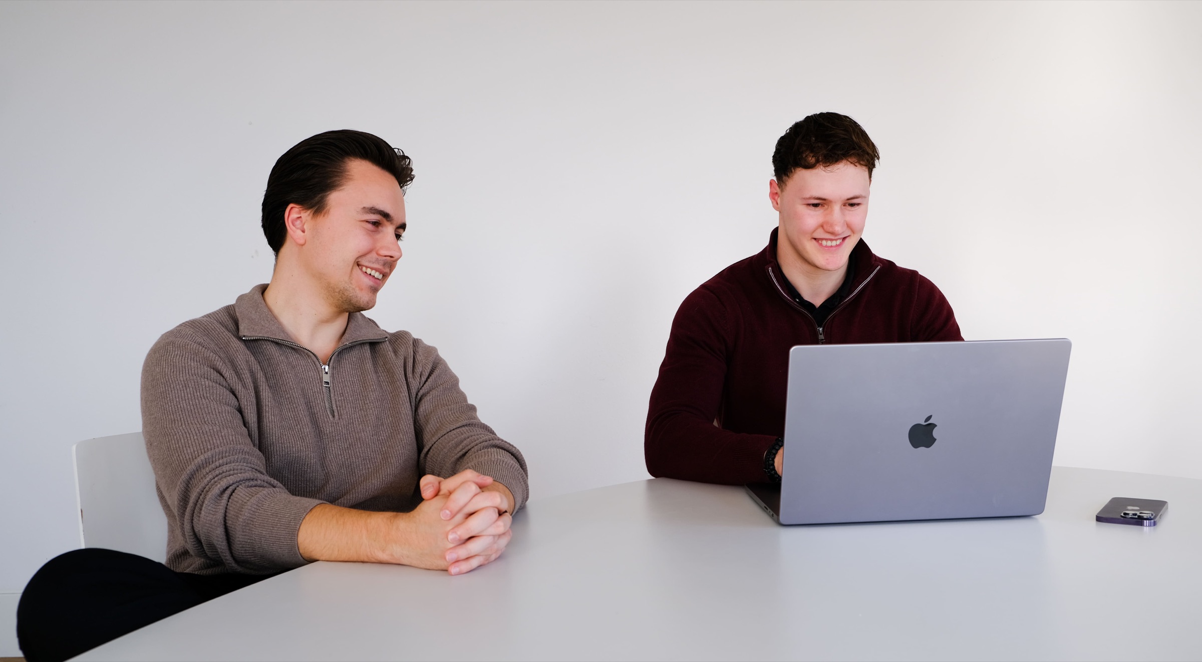 Twee teamleden van Tiкt in werksessie aan een witte tafel met laptop, lachend overleg op kantoor in Ede.